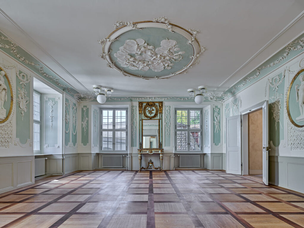Prunkvoller Saal mit Deckenstuck, türkisfarbenen Wandfeldern und geöltem Intarsienboden