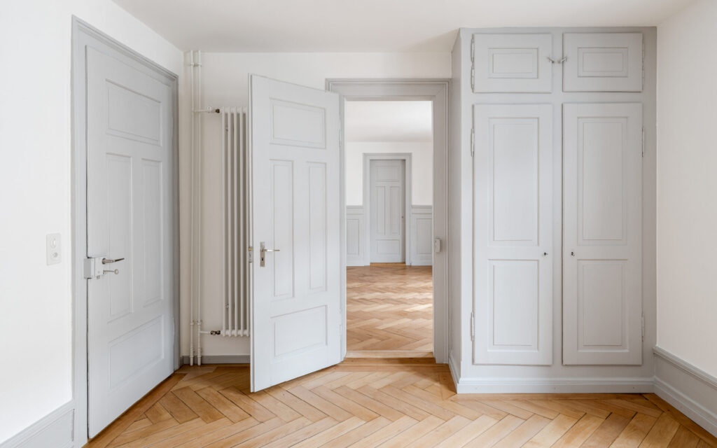Restaurierter Altbau-Innenraum mit Fischgrätparkett, weissen Türen und massgefertigtem Einbauschrank