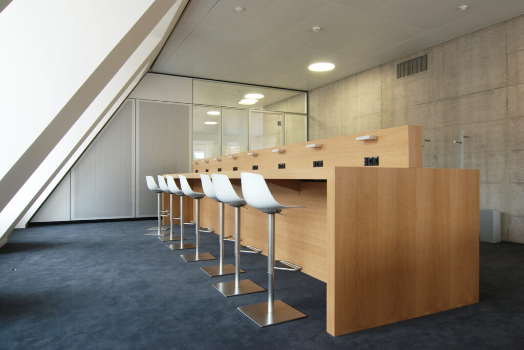 Massgefertigter EDV-Tisch mit Holzverkleidung und Barhockern im Büro mit Dachschräge