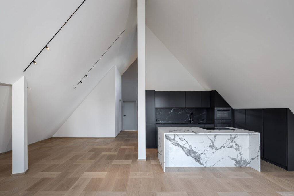Offene Dachwohnung mit moderner Küche und Kücheninsel aus Marmor sowie Parkettboden
