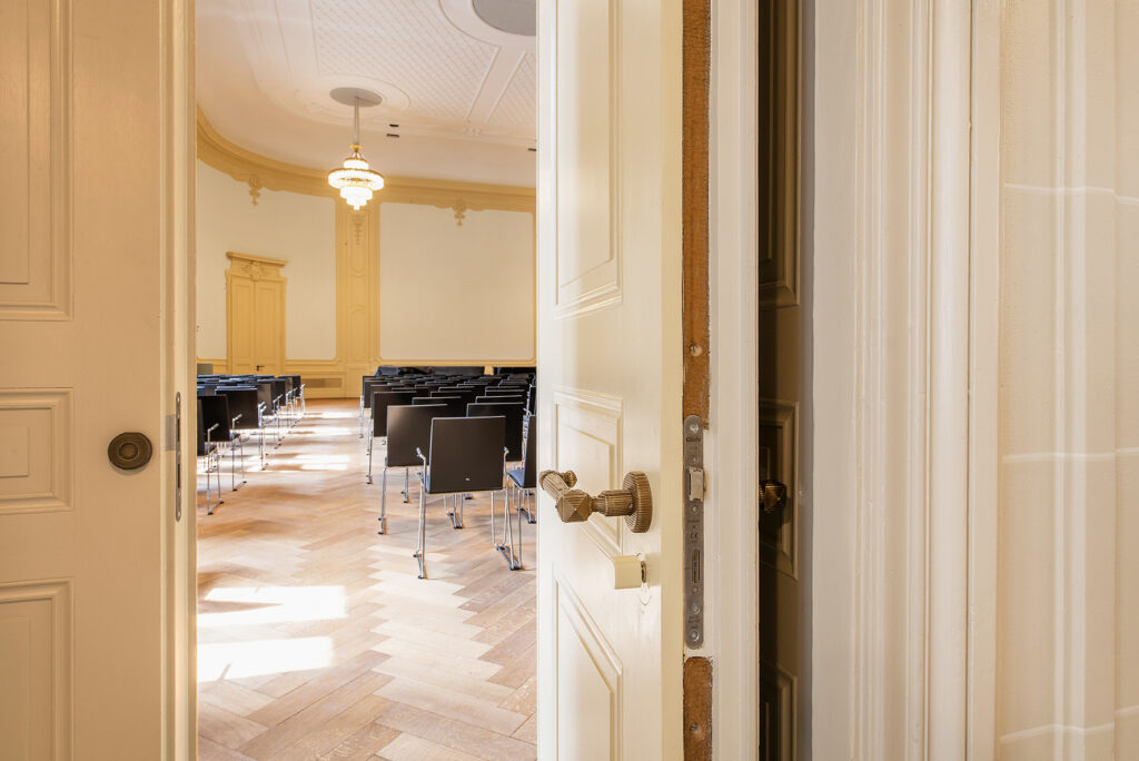 Blick durch eine geöffnete historische Holztür mit dem Historical Protector Brandschutzsystem in einen Saal des Stadtkasinos Basel.