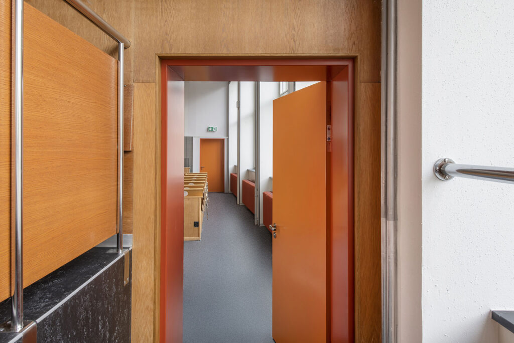Geöffnete orange Brandschutztür mit Blick in einen Hörsaal der ETH Zürich