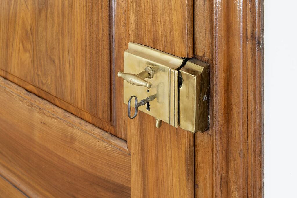 Detail einer historischen Holztür mit aufgesetztem Schloss, Türdrücker und eingestecktem Schlüssel